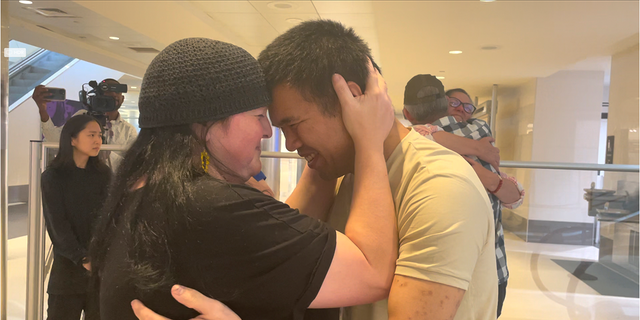 Andy Huynh, left, and Alex Drueke, far right, are seen hugging their loved ones after arriving at Birmingham-Shuttlesworth International Airport in Birmingham, Ala., Saturday, Sept. 24, 2022. The U.S. military veterans disappeared three months ago while fighting Russia with Ukrainian forces. They were released earlier this week by Russian-backed separatists as part of a prisoner exchange.